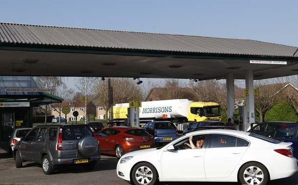 A petrol tanker driver makes a delivery as drivers queue for fuel in Loughborough