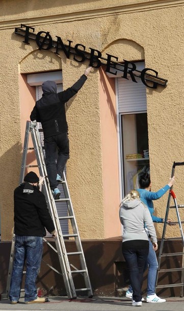 A worker mounts a sign with the new name "Tonsberg" at a clothing store of the Thor Steiner lable in Chemnitz