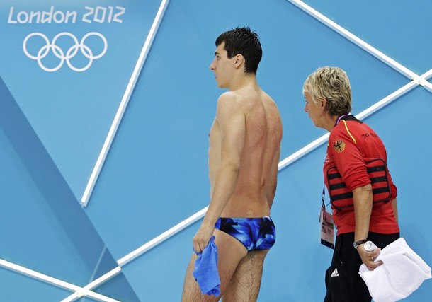 Germany's Stephan Feck leaves the pool deck with his coach after retiring injured, during the men's 3m springboard preliminary round at the London 2012 Olympic Games at the Aquatics Centre